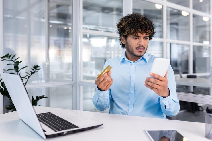 worried-young-hispanic-man-sitting-desk-office-looking-phone-upset-holding_321831-16664